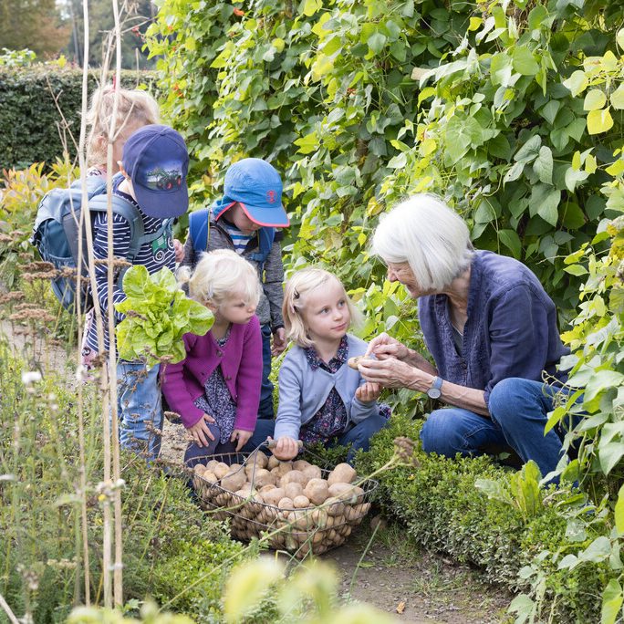Kinder mit einer erwachsenen Person im Garten